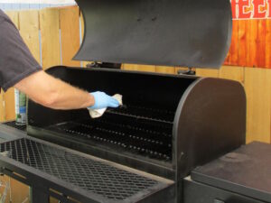 applying oil to the grates of the Tahoma 900 smoker while still warm