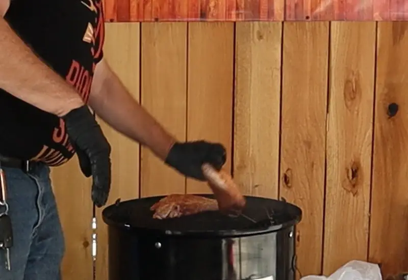 Turkey thighs being placed in Weber Smokey Mountain Cooker